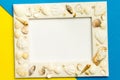 Photo frame with shells on blue and yellow color paper texture background. Royalty Free Stock Photo