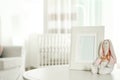 Photo frame and toy bunny on table in baby room interior. Space for text