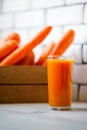 Photo of fresh carrots in a wooden box and a glass of freshly squeezed juice