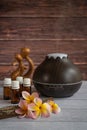 Brown essential oil diffuser with frangipani flowers, and small wooden love statue