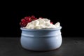 Photo of fresh natural cottage cheese with red currant in a blue ceramic bowl on the black stone plate. Organic eco healthy meal, Royalty Free Stock Photo