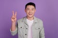 Photo of friendly cheerful korean man show v-sign isolated violet color background