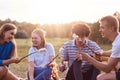 Photo of friendly company of friends have picnic outdoor, roast marshmallows over campfire, have positive expressions, pleasant li