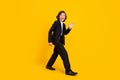 Photo of friendly excited crazy little boy walk wave hand wear black uniform shoes isolated yellow color background