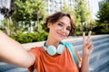 Photo of friendly funky girl dressed orange t-shirt eyewear backpack showing v-sign recording video vlog outdoors urban Royalty Free Stock Photo