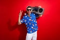 Photo of friendly guy showing v sign clubber holding old school boombox for christmas eve discotheque isolated on red Royalty Free Stock Photo