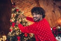 Photo of friendly happy guy enjoying decorate hanging baubles fir tree for new year atmosphere at home wearing red