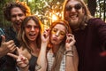 Photo of friendly hippie people men and women, smiling and taking selfie in forest Royalty Free Stock Photo