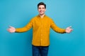 Photo of friendly hospitable guy invite embrace wear yellow shirt jeans isolated blue color background