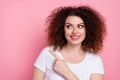 Photo of friendly woman with perming coiffure dressed white t-shirt look directing at promo empty space isolated on pink