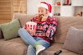 Photo of frightened young male wear ugly sweater sit sofa watch movie terrified horror film bite fingers eat popcorn at