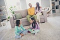 Photo of full family four members sit couch floor two little children have chat wear colorful jumper trousers in living