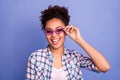 Photo of funky adorable young woman wear plaid shirt smiling arm pink eyeglasses isolated violet color background Royalty Free Stock Photo