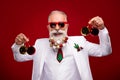 Photo of funky charming age gentleman wear new year costume dark eyewear holding red balls isolated red color background