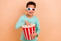 Photo of funky cheerful boy enjoy new movie 3d glasses eat popcorn big box isolated on beige color background Royalty Free Stock Photo