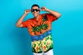 Photo of funky cheerful guy dressed print shirt hands arms dark eyewear isolated blue color background Royalty Free Stock Photo