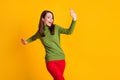 Photo of funky cheerful lady raise arms dance wear green pullover sweater red trousers isolated yellow color background Royalty Free Stock Photo