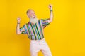 Photo of funky cool guy dressed striped shirt screaming looking empty space rising fists isolated yellow color Royalty Free Stock Photo