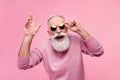 Photo of funky cool mature man dressed pullover arm dark glasses smiling waving arm hello isolated pink color background