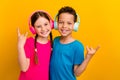 Photo of funky cool preteen schoolchildren wear t-shirts enjoying music showing hard rock signs isolated yellow color Royalty Free Stock Photo