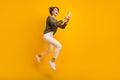 Photo of funky crazy cool girl wearing stylish clothes running empty space reading social media isolated on yellow color Royalty Free Stock Photo