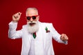 Photo of funky elder grey hair man dance wear eyewear white jacket isolated on red color background Royalty Free Stock Photo