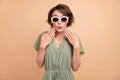 Photo of funky excited happy young woman hand face wear sunglass news astonished isolated on beige color background Royalty Free Stock Photo