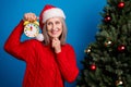 Photo of funky grey hairdo old lady look clock near tree wear red pullover cap isolated on blue color background