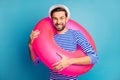 Photo of funky handsome guy summer tourist walking seaside hold colorful pink rubber lifebuoy swimming time wear striped