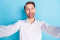 Photo of funky happy crazy young man take selfie make funny face fooling isolated on blue color background Royalty Free Stock Photo