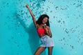 Photo of funky happy dark skin positive young woman sing song mic fall confetti isolated on blue color background