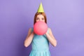 Photo of funky happy young woman blow air balloon party decoration inflate isolated on purple color background