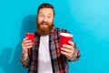 Photo of funky optimistic man with stylish beard dressed checkered shirt give you plastic red cup isolated on blue color Royalty Free Stock Photo