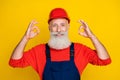 Photo of funky positive age man workwear overall red hard hat showing two okey gestures isolated yellow color background Royalty Free Stock Photo