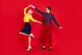 Photo of funky positive funny young lady guy dressed pinup outfits dancing swing isolated red color background Royalty Free Stock Photo