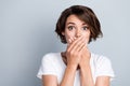 Photo of funky scared woman dressed white t-shirt arms close mouth empty space grey color background