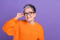 Photo of funky thoughtful woman dressed orange sweater arm eyewear looking empty space isolated violet color background