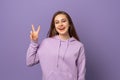 Photo of funny adorable young woman hand fingers show v-sign symbol, peace gesture, with a happy smile on face, standing over Royalty Free Stock Photo