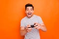 Photo of funny attractive cheerful guy hold hands joystick playing video games excited gamer riding speed car to finish
