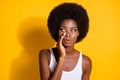 Photo of funny black young girl look empty space palm mouth whisper wear white tank-top isolated yellow color background Royalty Free Stock Photo