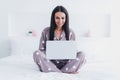 Photo of funny charming young woman nightwear sitting bed writing modern gadget inside indoors home room