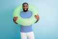 Photo of funny cheerful dark skin guy hold green life buoy around neck ready swim ocean sea traveler good mood sunny day