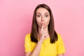 Photo of funny confident young woman dressed yellow t-shirt finger mouth asking keep silence isolated pink color