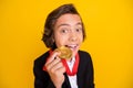 Photo of funny crazy boy teeth bite winner medal wear black uniform isolated yellow color background Royalty Free Stock Photo