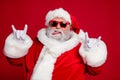 Photo of funny crazy rude careless old man show horns protrude tongue wear santa hat costume isolated red color Royalty Free Stock Photo