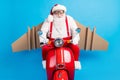 Photo of funny crazy santa claus ride scooter fast speed with cardboard craft wings fly in sky wear modern stylish Royalty Free Stock Photo