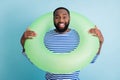 Photo of funny dark skin guy holding green life buoy around neck ready swim ocean sea addicted traveler good mood sunny