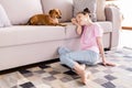 Photo of funny dreamy small schoolgirl dressed pink t-shirt siting couch looking dachshund puppy indoors room home house