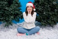 Photo of funny excited girl dressed santa claus helper hat arms cheeks enjoying x-mas snowfall  blue color Royalty Free Stock Photo