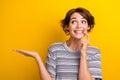 Photo of funny excited good mood woman dressed striped t-shirt look empty space palm show object isolated on yellow